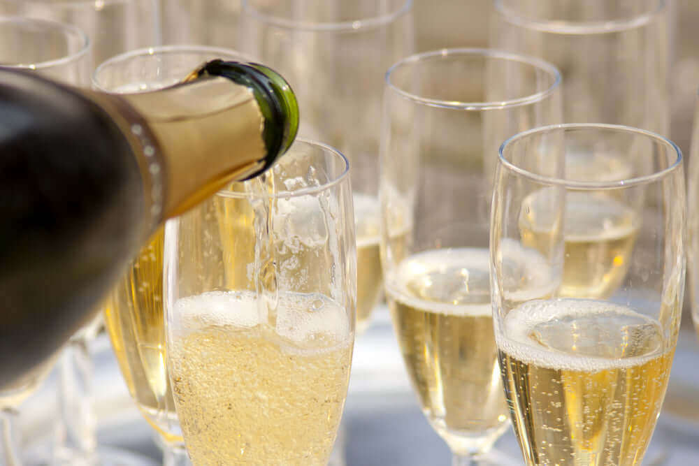 Pouring sparkling wine into glasses, showcasing options for sparkling wine for under 20.