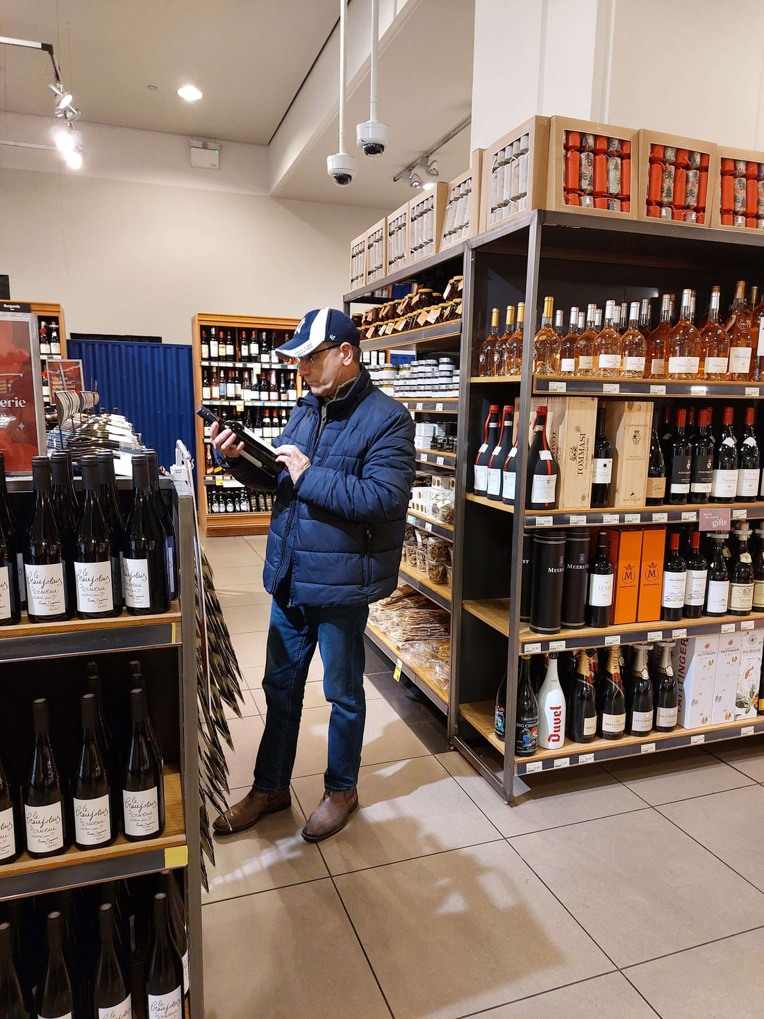 Person reviewing supermarket private label wines in a well-stocked wine aisle at a grocery store.